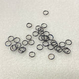 Collection of small metal connector rings on a textured white surface