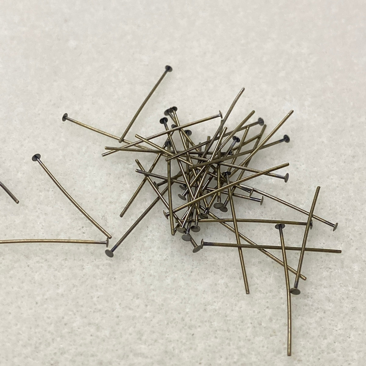 Pile of metal  jewelry making pins on a textured white surface