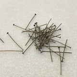 Pile of metal  jewelry making pins on a textured white surface