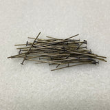 Pile of metal  jewelry making pins on a textured white surface