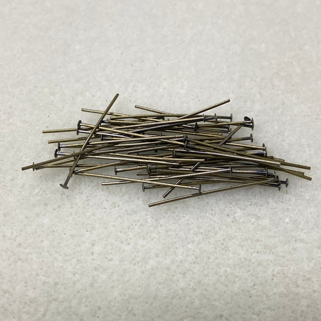 Pile of metal  jewelry making pins on a textured white surface