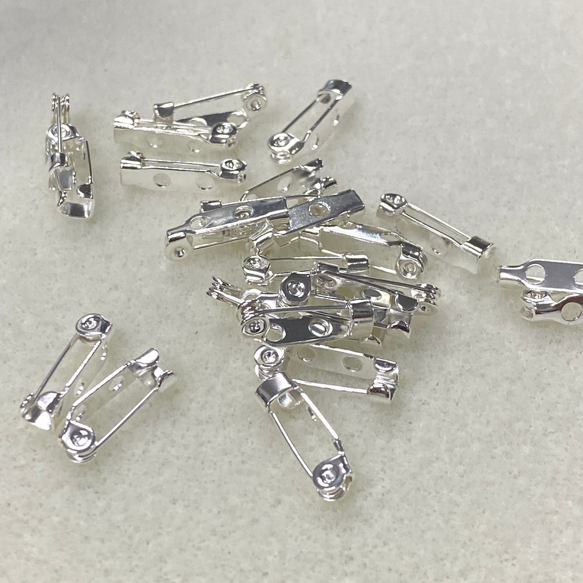 Silver brooch pins on a light gray background
