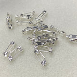 Silver brooch pins on a light gray background