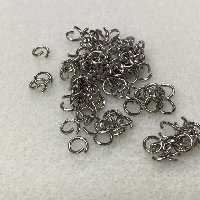 Pile of silver jump rings on a light gray background