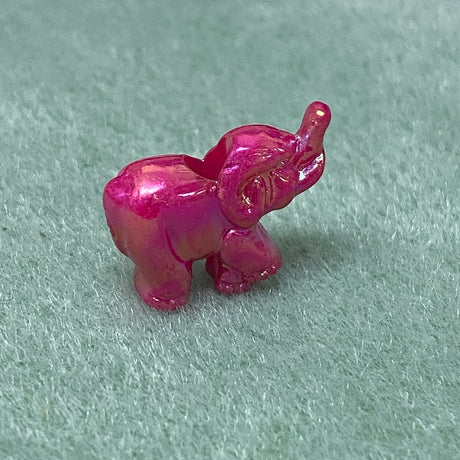 A brightly colored plastic elephant-shaped bead, with a shoelace hole, intended for craft and jewelry making.