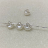 Pearl buttons on a thin wire against a light gray background