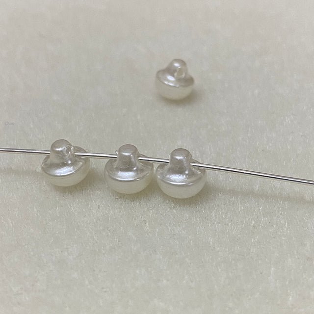 Pearl buttons on a thin wire against a light gray background