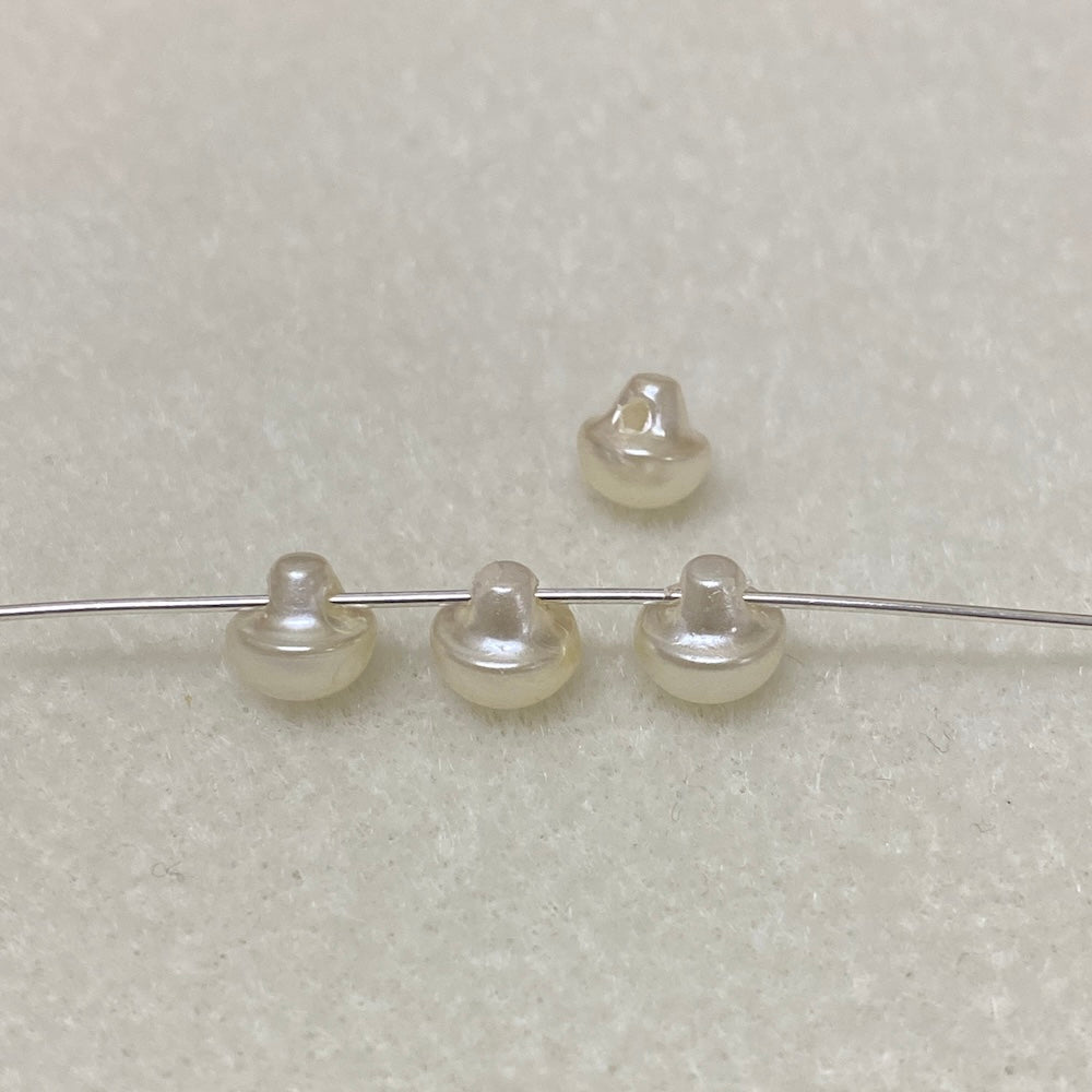 Four pearl buttons on a wire against a light gray background