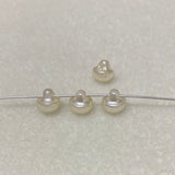 Four pearl buttons on a wire against a light gray background