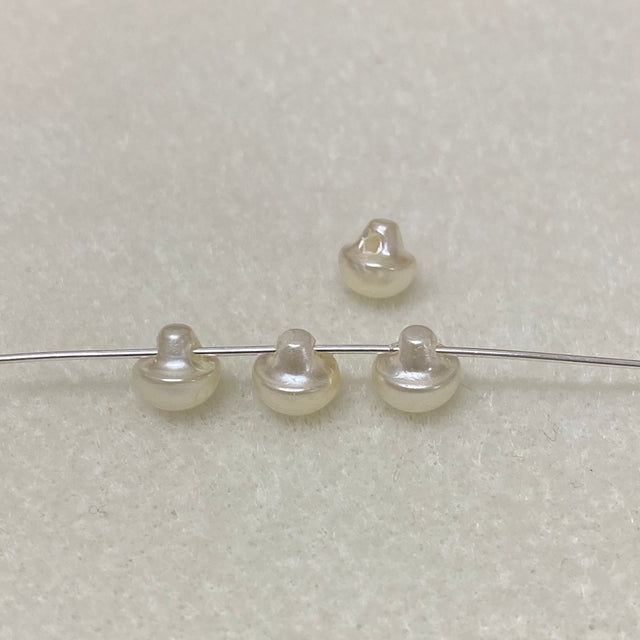 Four pearl buttons on a wire against a light gray background