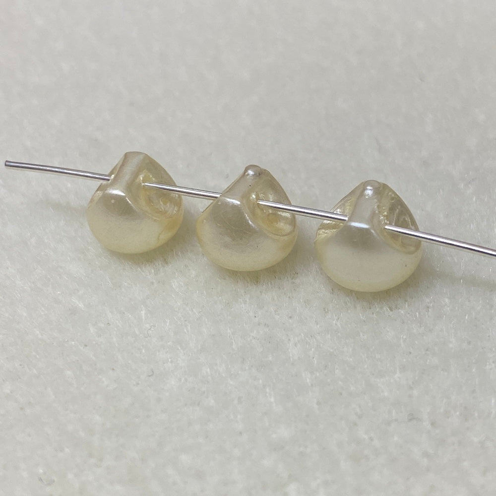 Three pearl buttons on a thin metal rod against a light gray background