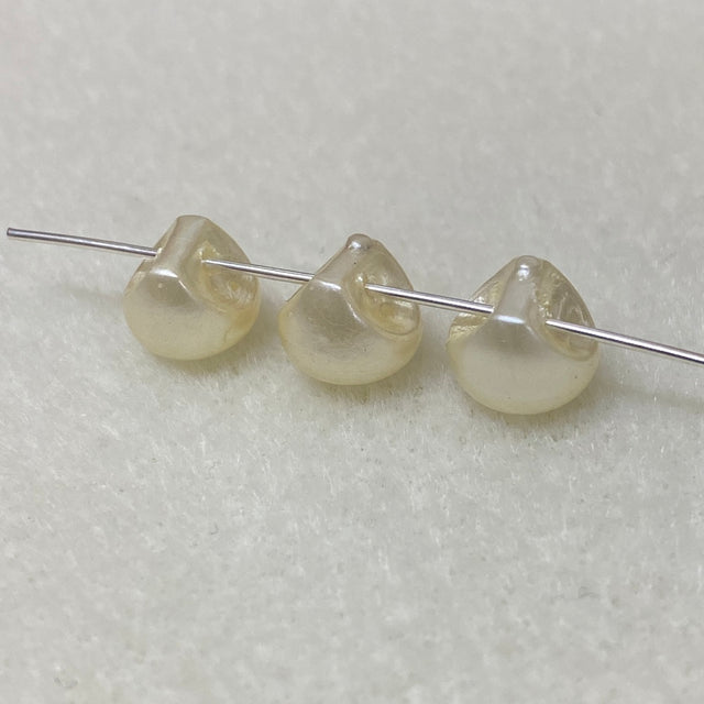 Three pearl buttons on a thin metal rod against a light gray background
