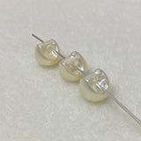 Three pearl buttons on a needle against a textured white background