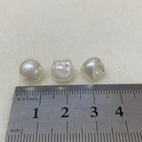 Three pearl buttons on a ruler for size reference