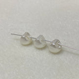 Three pearl buttons on a thin wire against a light gray background
