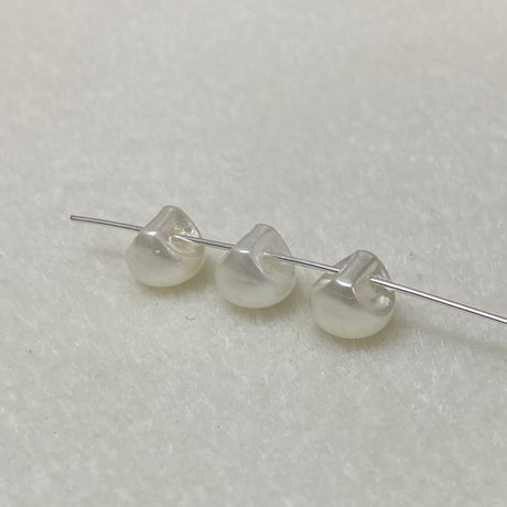 Three pearl buttons on a thin wire against a light gray background