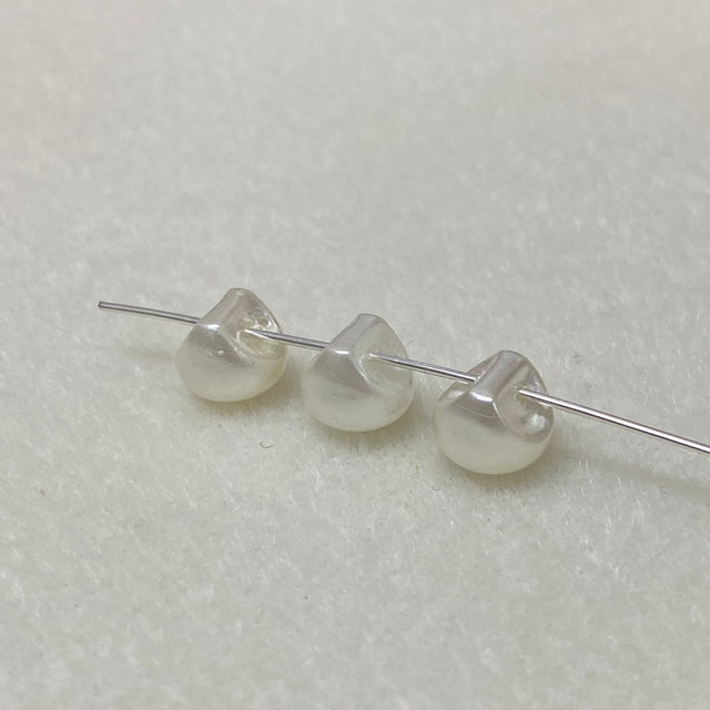 Three pearl buttons on a thin wire against a light gray background