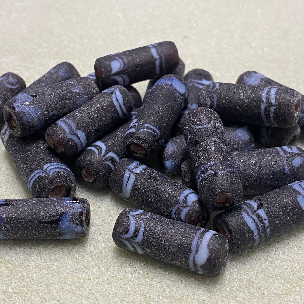Dark brown beads with blue stripes on a beige surface
