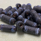 Collection of dark purple beads with white stripes on a light beige background