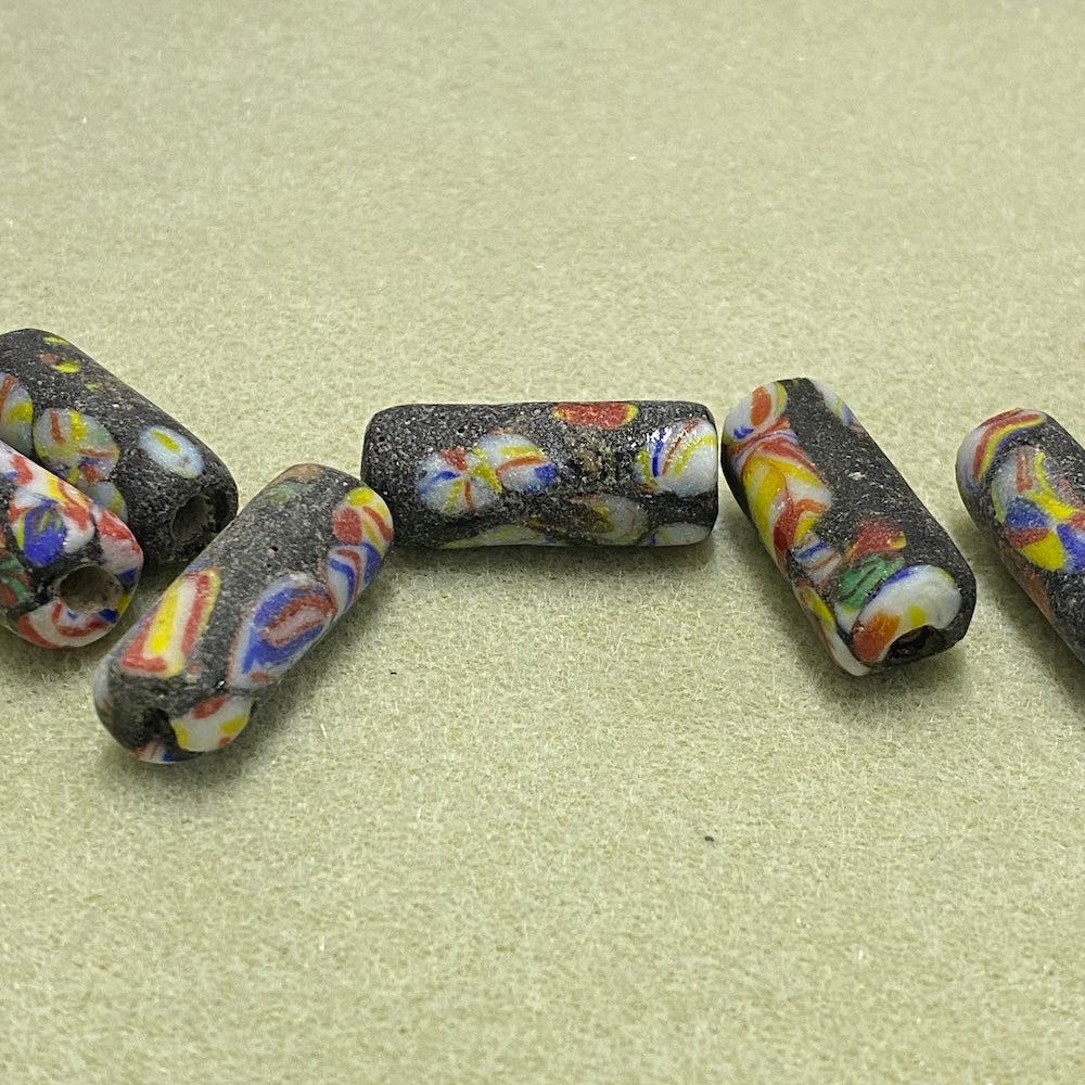 Colorful beads with black speckles on a beige surface
