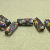 Colorful beads with black speckles on a beige surface