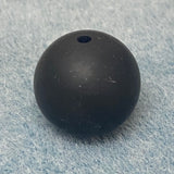 Black round silicone bead on a textured gray background