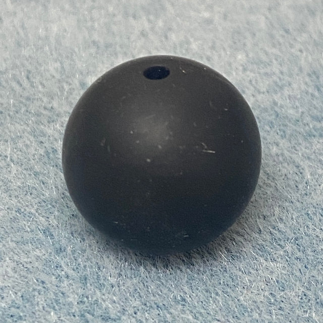 Black round silicone bead on a textured gray background