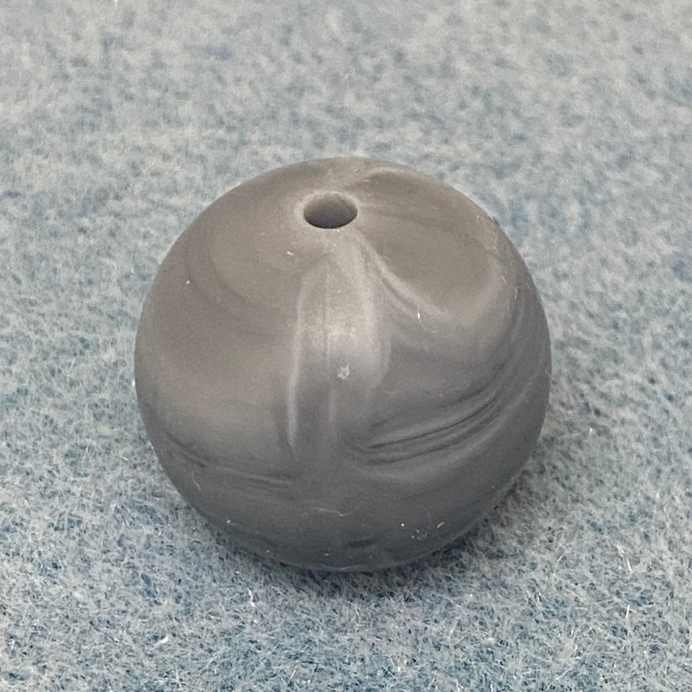 grey and white swirl round silicone bead on a textured gray background