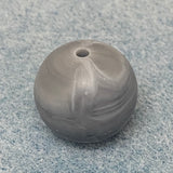 grey and white swirl round silicone bead on a textured gray background