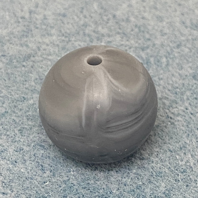 grey and white swirl round silicone bead on a textured gray background