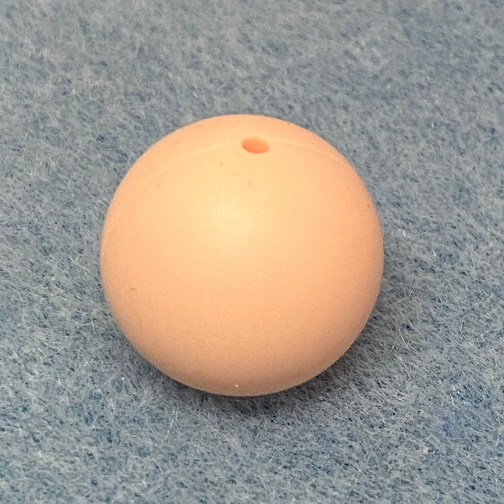 blush pink round silicone bead on a textured gray background
