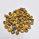 A collection of sand earth mustard blue vintage faience beads arranged in a pile, with varying shapes colors and textures.