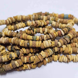 A collection of sand colored vintage faience beads arranged in lines, with varying shapes and textures.