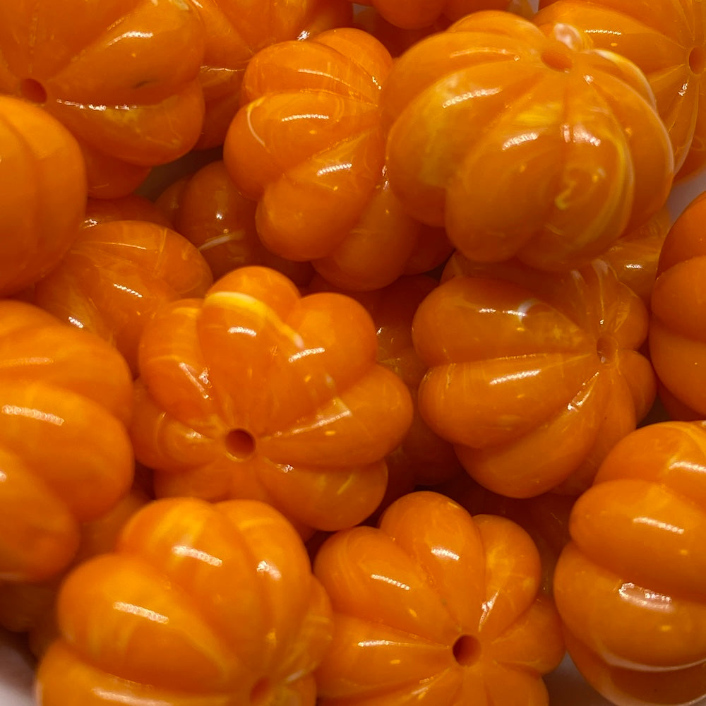 A close-up image of orange pumpkin-shaped vintage beads with a marbled effect.