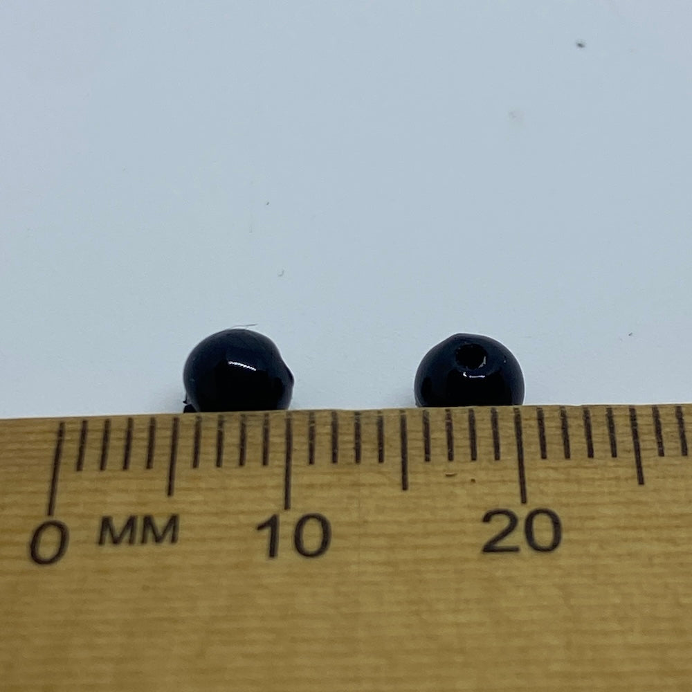 Two black beads on a wooden ruler with measurement markings.