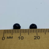 Two black beads on a wooden ruler with measurement markings.