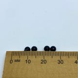 Four black beads on a wooden ruler against a white background