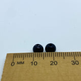 Two black beads on a ruler for size reference against a white background