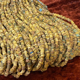 A collection of colored vintage faience beads arranged in lines, with varying shapes and textures.