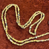 A collection of colored faience beads arranged in a loop, with varying shapes and textures.