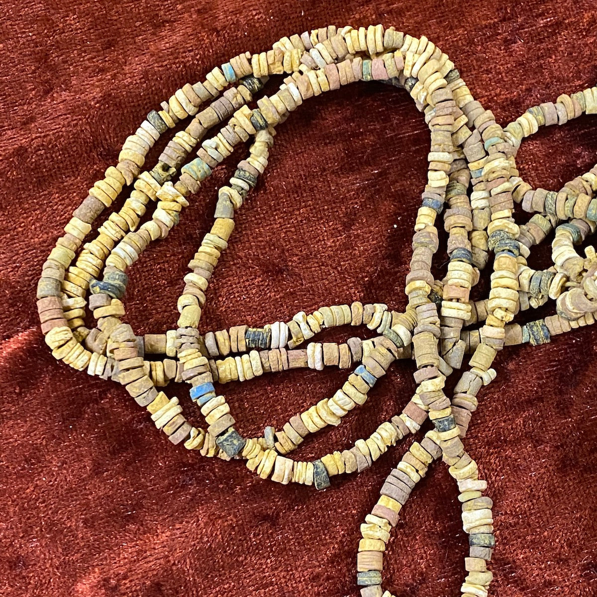 A collection of colored faience beads arranged in a loop, with varying shapes and textures.
