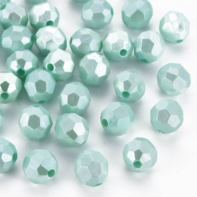 Light mint green faceted glass beads scattered on a white background.