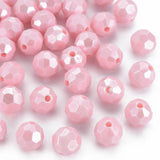 Pink faceted round beads with a central hole, scattered on a plain white background.