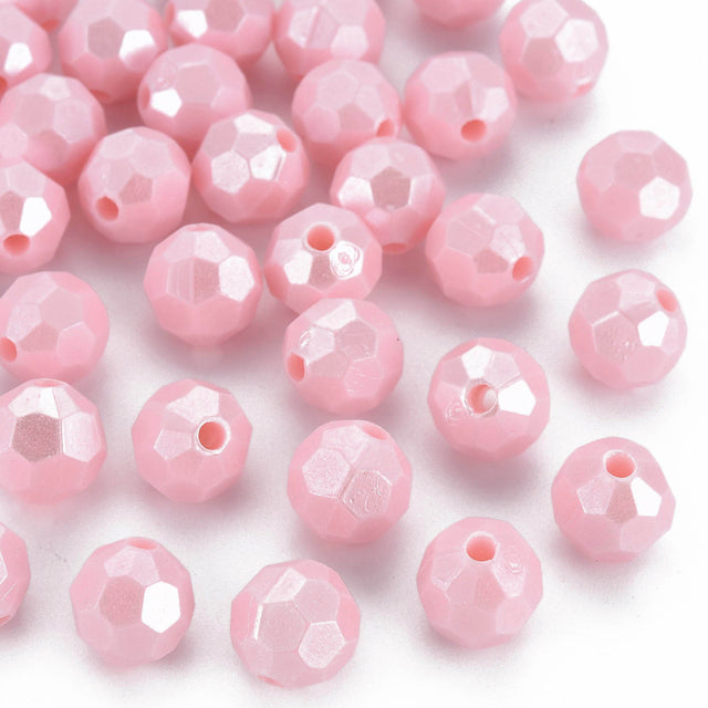 Pink faceted round beads with a central hole, scattered on a plain white background.