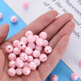 A hand holding a pile of small faceted light pink beads, with a few additional beads scattered on a blue and white background.