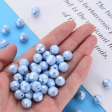 A hand holding a pile of light blue faceted round beads, with additional loose beads scattered on a blue and white background with printed text.