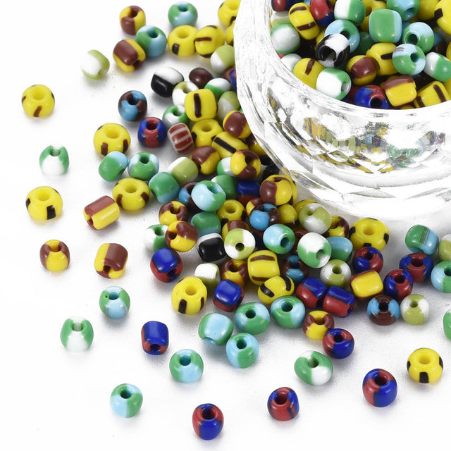 Colorful beads scattered on a white surface with a clear container filled with beads.