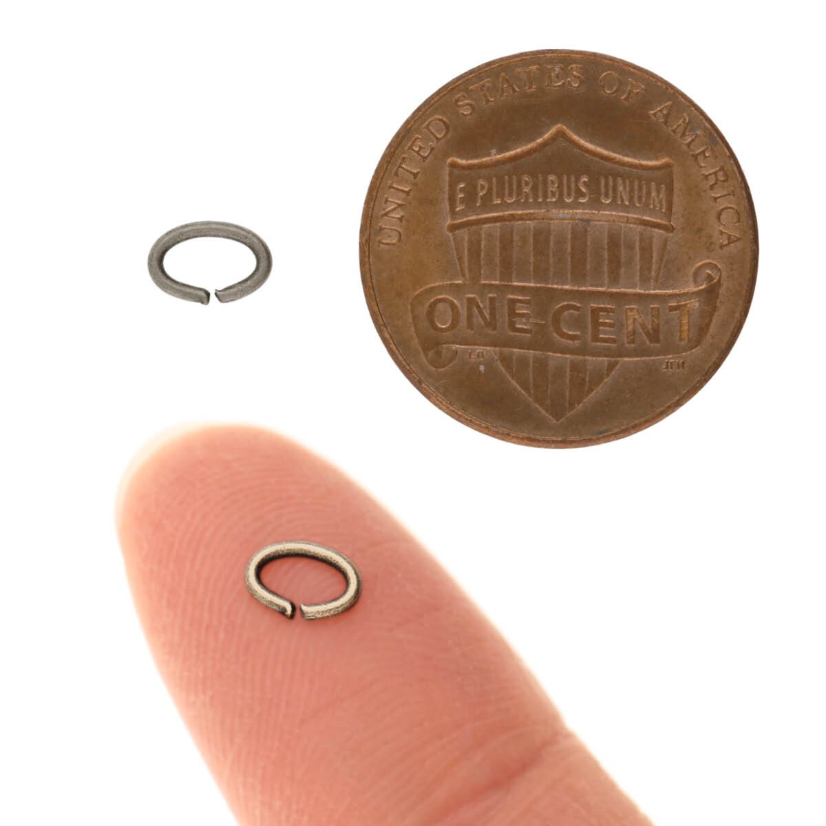 Small metal ring on a finger next to a penny