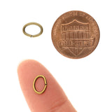 Two small metal oval jump rings with  on a white background