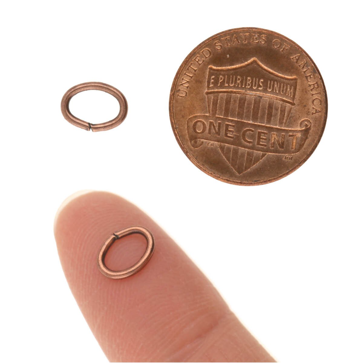 Copper jump ring on a finger next to a penny